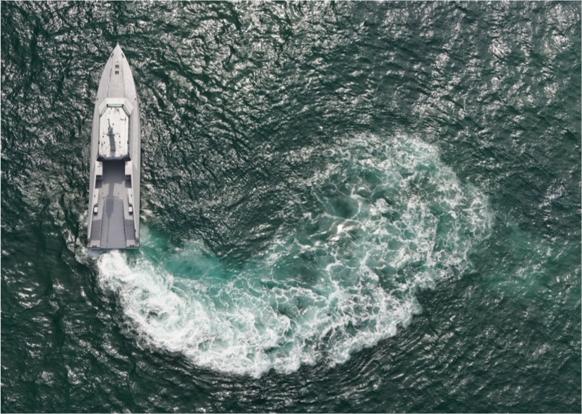Aerial view of a naval vessel maneuvering at sea